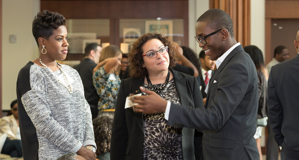 two woman looking as a black man share thoughts in a suit