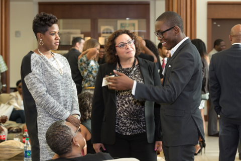 Two woman looking as a black man share thoughts in a suit